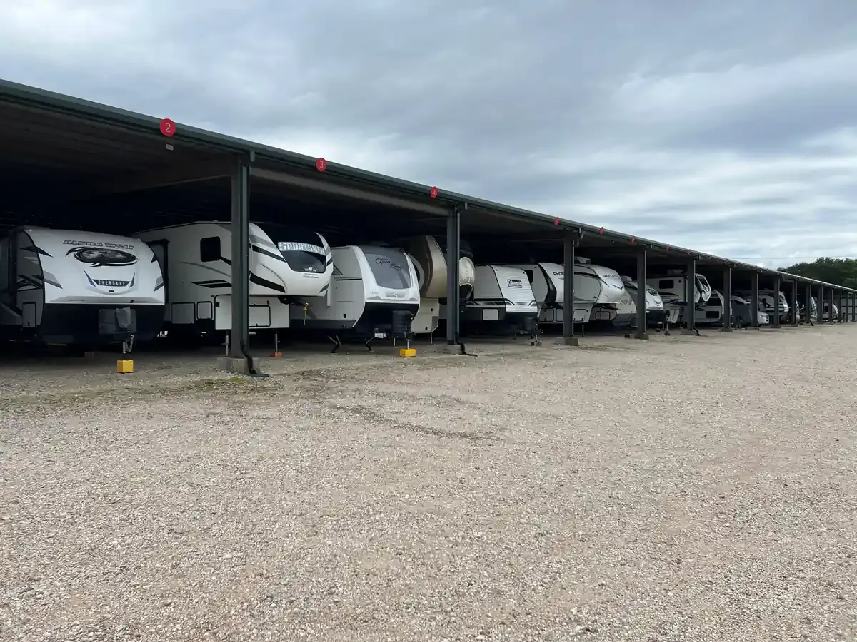 RVs under a covered awning on gravel driveway
